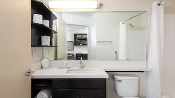 A modern bathroom with a white sink, black vanity, and a large mirror.