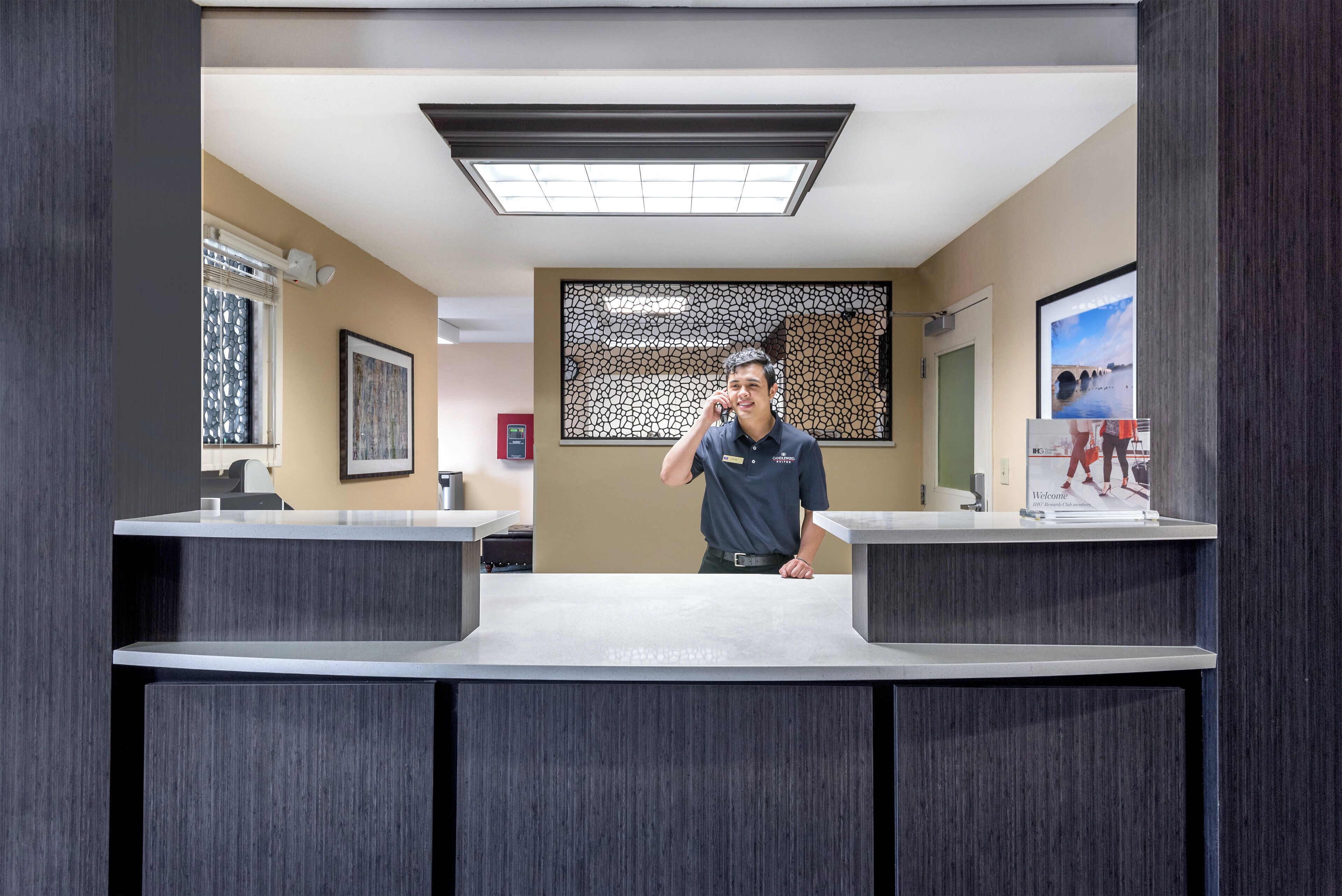 A reception area with a modern design, including a reception desk, a decorative wall, and a framed welcome sign.