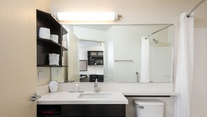 A modern bathroom with a white sink, black cabinets, a hair dryer, and a toilet. - Candlewood Suites Washington Dulles Sterling by IHG (Sterling)