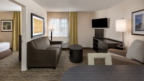 A hotel room with a sofa, a small table, a TV, and a bed. - Candlewood Suites Washington Dulles Sterling by IHG (Sterling)