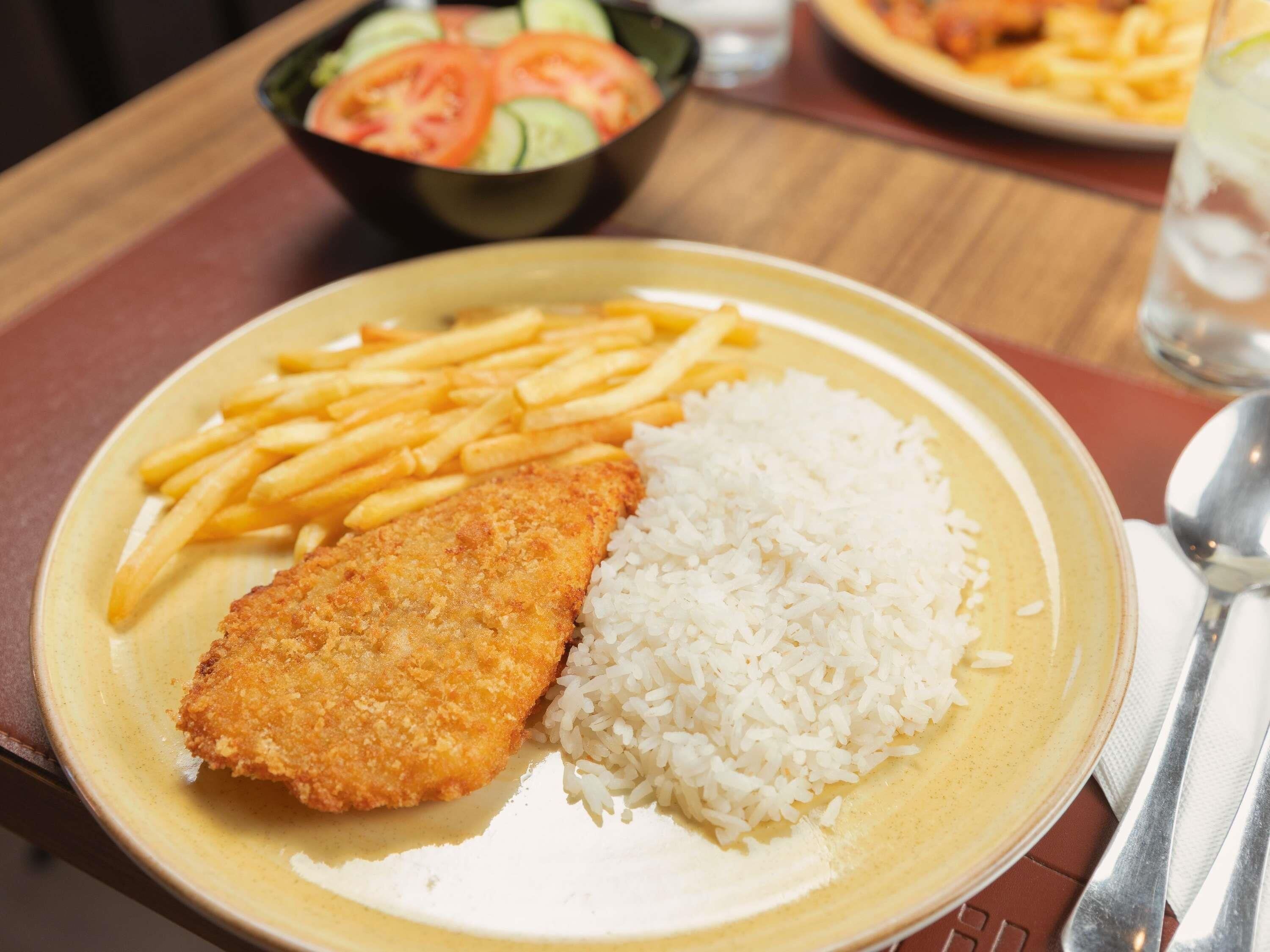 Un plato con milanesa, papas fritas y arroz blanco.
