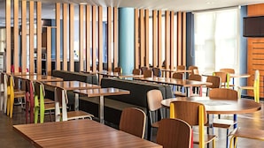 A modern restaurant with wooden partitions, colorful chairs, and a flat-screen TV mounted on the wall. - ibis Sao Paulo Interlagos (São Paulo)