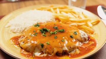 A plate with a meat dish, fries, and rice.