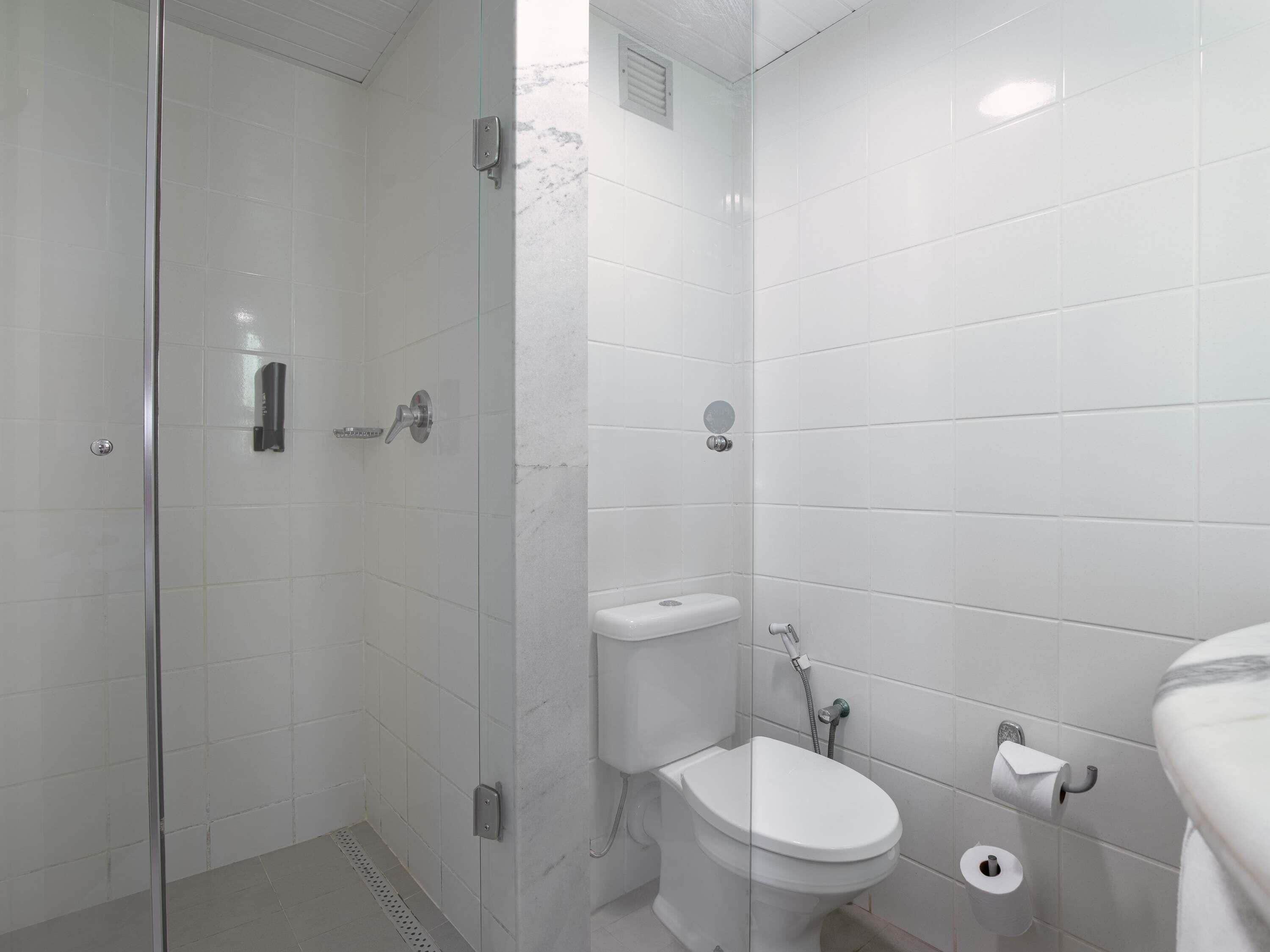 A modern bathroom with a glass shower enclosure, a toilet, and a bidet.