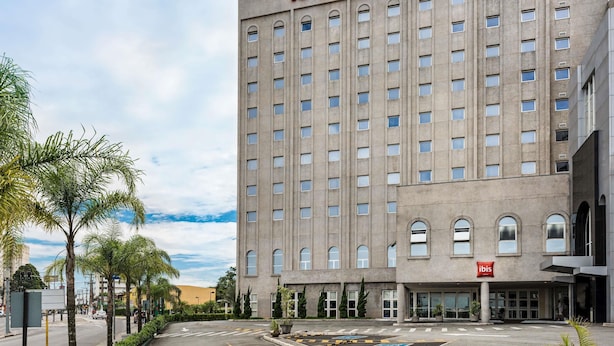 Un bâtiment d'hôtel avec une enseigne « IBIS HOTEL » bien visible, une façade symétrique aux fenêtres régulièrement espacées et un toit plat.