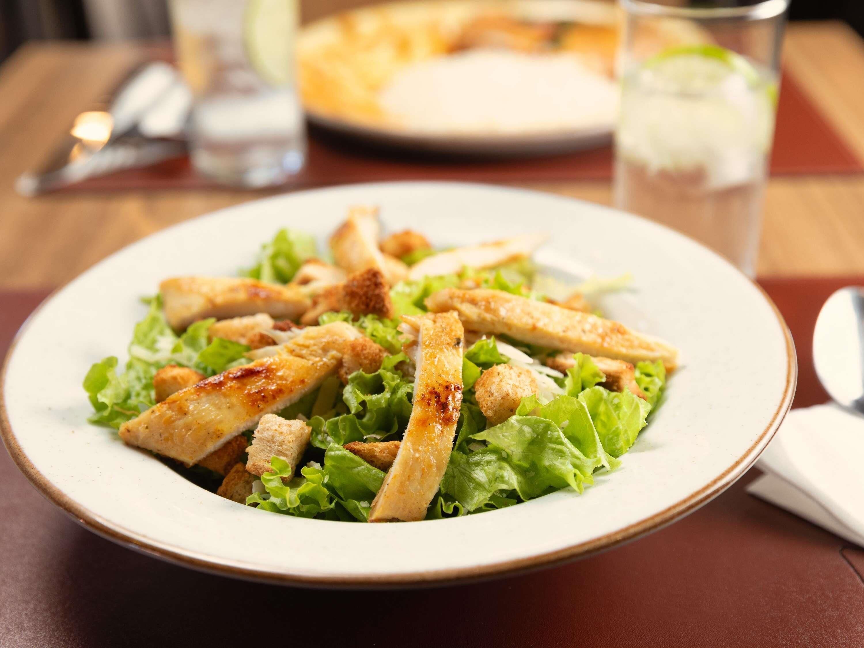 A plate of salad with croutons and lettuce on a table.