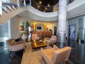 Relax in our spacious lobby with comfortable seating and a lush potted plant.