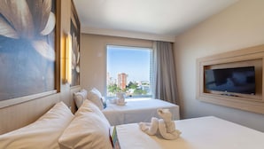 A hotel room with two beds, a TV, a window with a city view, and a painting on the wall. - Mercure Manaus Hotel (Manaus)