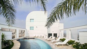 A modern building with a swimming pool, lounge chairs, and a clear view of the city. - Mercure Manaus Hotel (Manaus)
