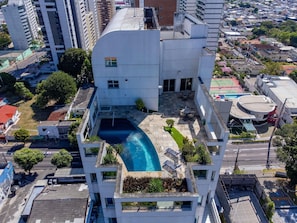 A modern building with a rooftop pool, surrounded by greenery and adjacent to a busy street. - Mercure Manaus Hotel (Manaus)