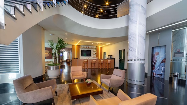 A spacious lobby with a curved staircase, a reception desk, seating area, and a large pillar. - Mercure Manaus Hotel (Manaus)