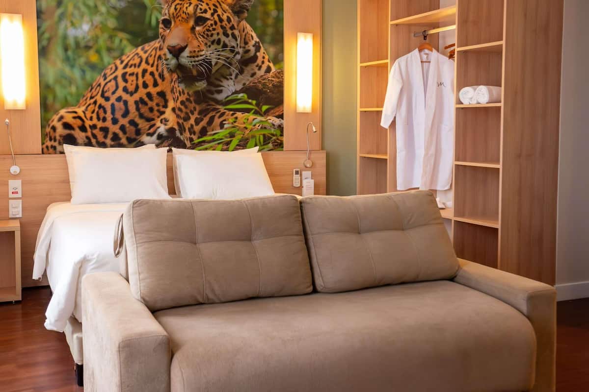 A bedroom with a bed, a sofa, a wardrobe, and a large leopard mural.