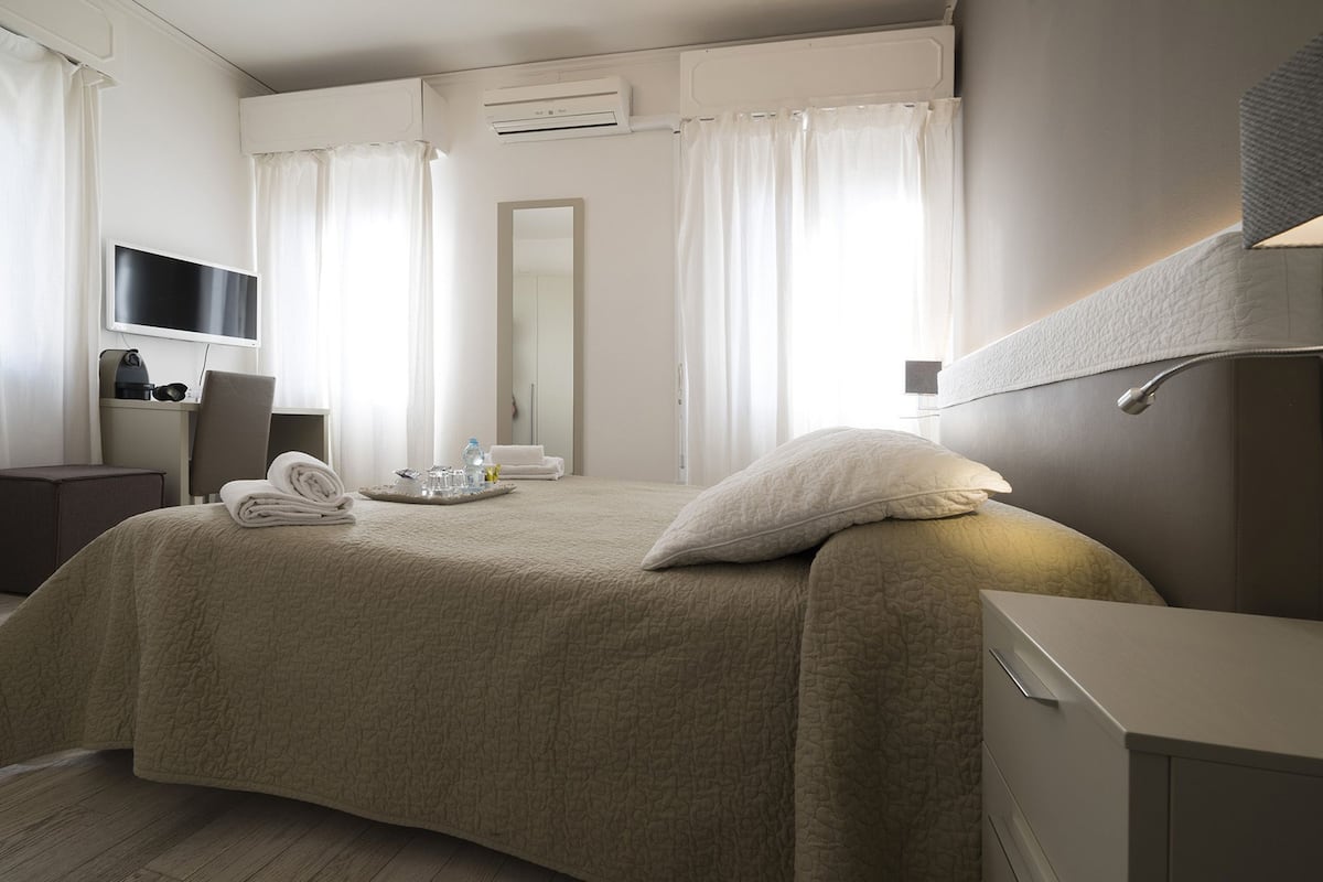 A hotel room with a bed, a TV, a desk, and a bathroom.