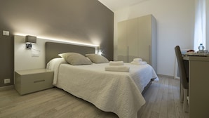 Een moderne slaapkamer met een bed, nachtkastjes, een kledingkast en een bureau.