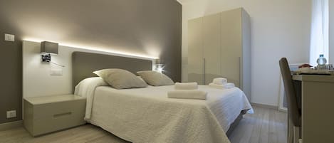 A modern bedroom with a bed, bedside tables, a wardrobe, and a desk.