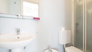 Een badkamer met een witte wastafel, toilet en een douchecabine met glazen wanden.
