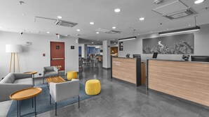 Un moderno vestíbulo de hotel con una recepción, una zona de estar y vistas al comedor.
