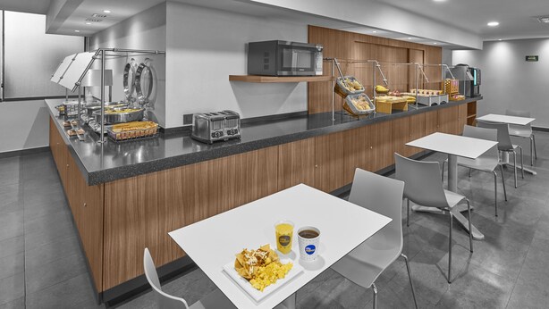 Un área de cocina moderna con una isla central, equipada con microondas, tostadora y diversos alimentos.