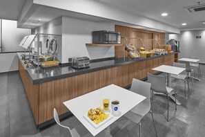 A modern kitchen area with a central island, equipped with a microwave, toaster, and various food items. - City Express by Marriott Ciudad Juarez (Ciudad Juárez)