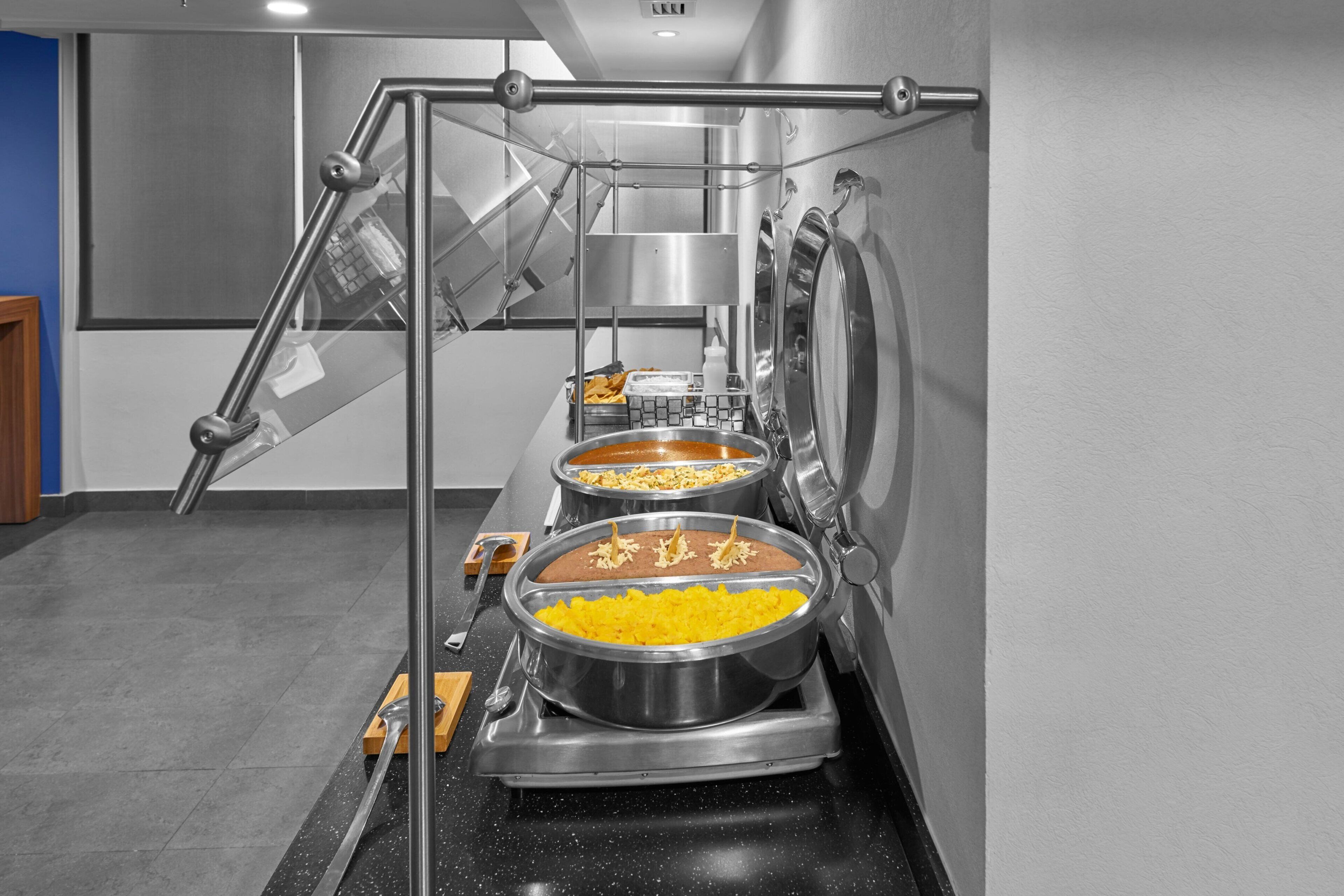 Montaje de bufé con varias estaciones de servicio, incluyendo platos como arroz y postres.