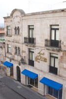 A historic building with a sign reading "Hotel & Suite Galeria." It features multiple balconies and a row of blue awnings.