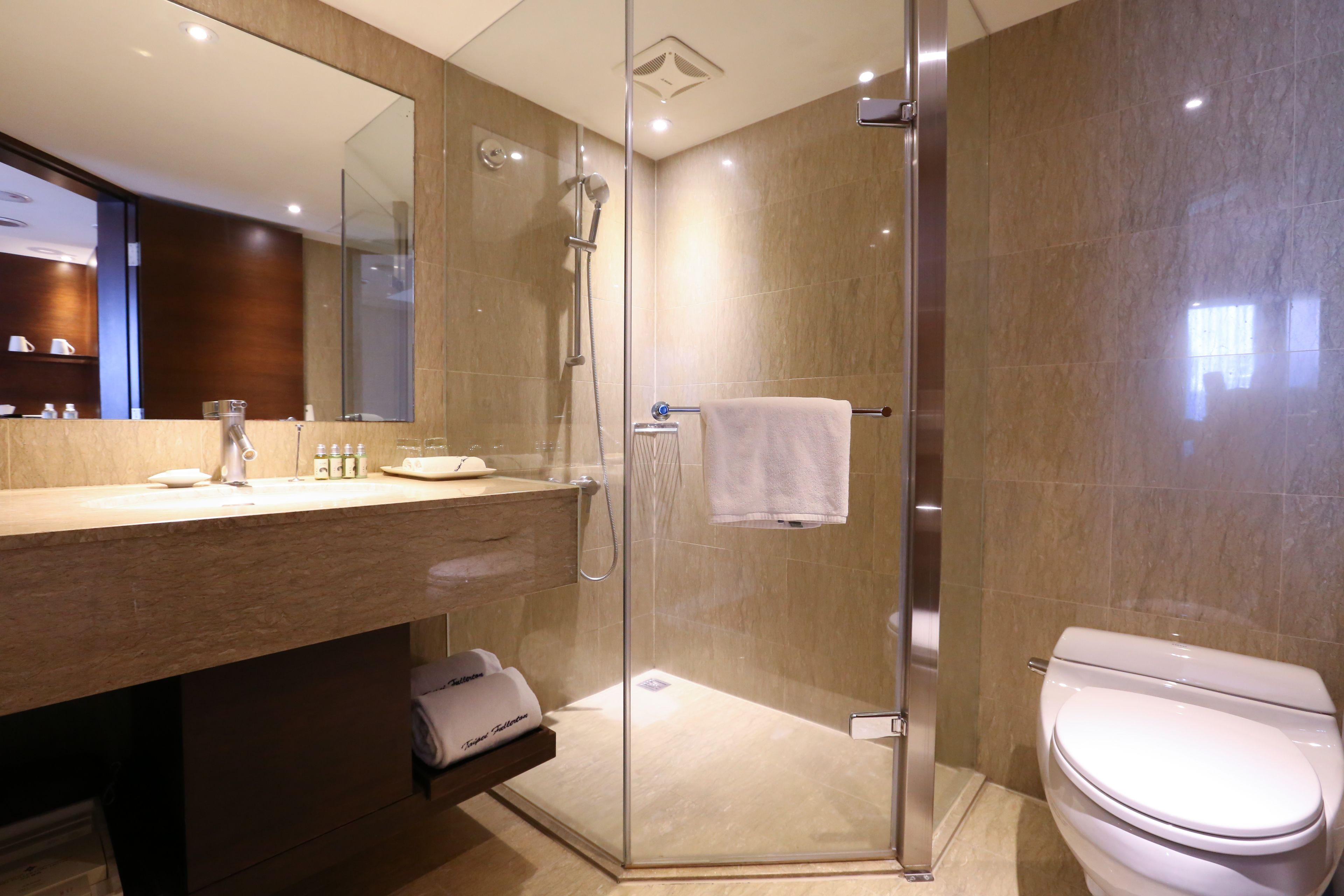 Un baño moderno con ducha envuelta en vidrio, inodoro blanco y tocador con espejo.