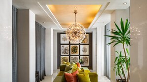 Ein moderner Flur mit einem grünen Sofa, dekorativen Kissen, einer großen Pflanze und gerahmten Kunstwerken an der Wand.