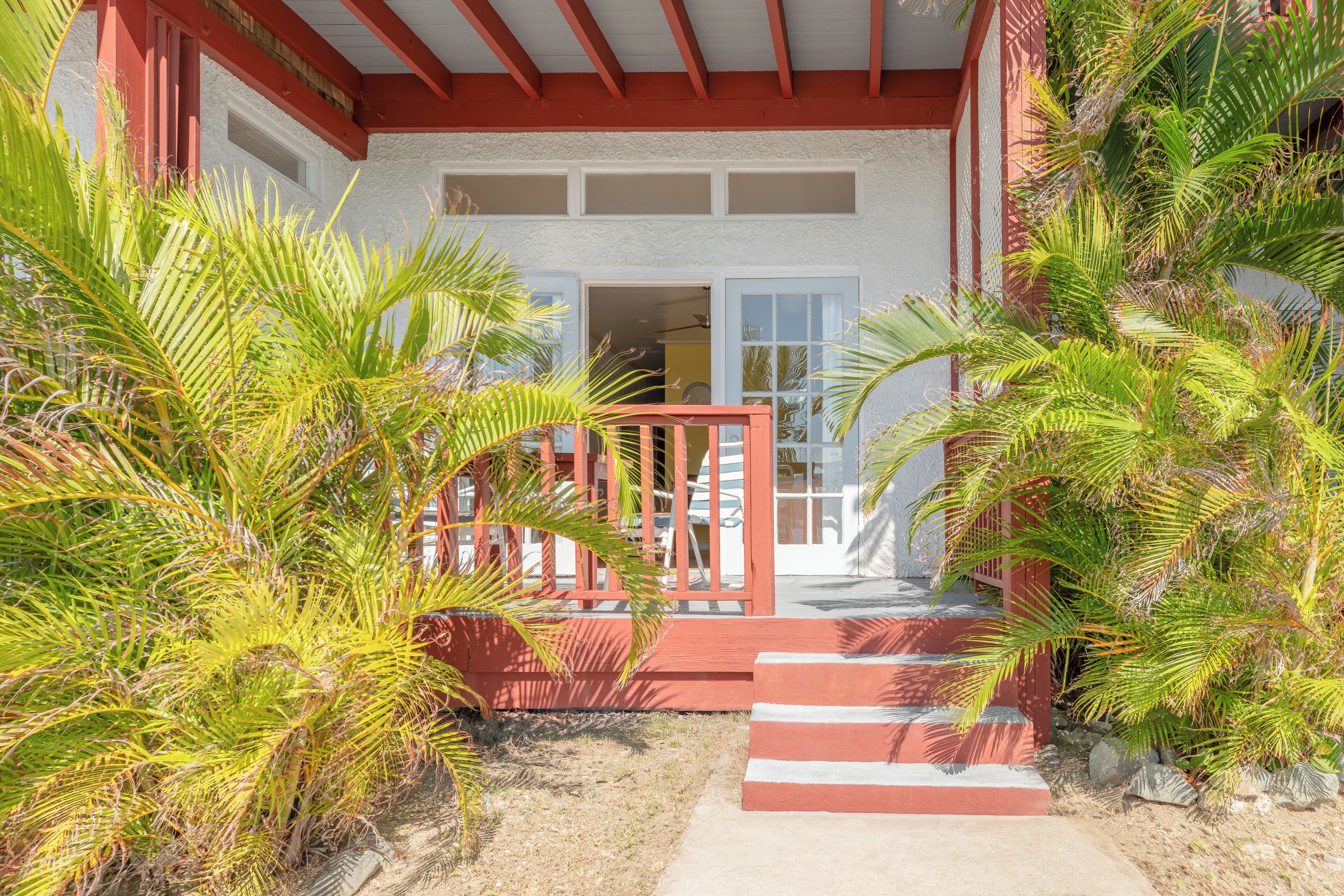 A building with a red exterior, a white upper section, and a red porch with steps leading to a door.