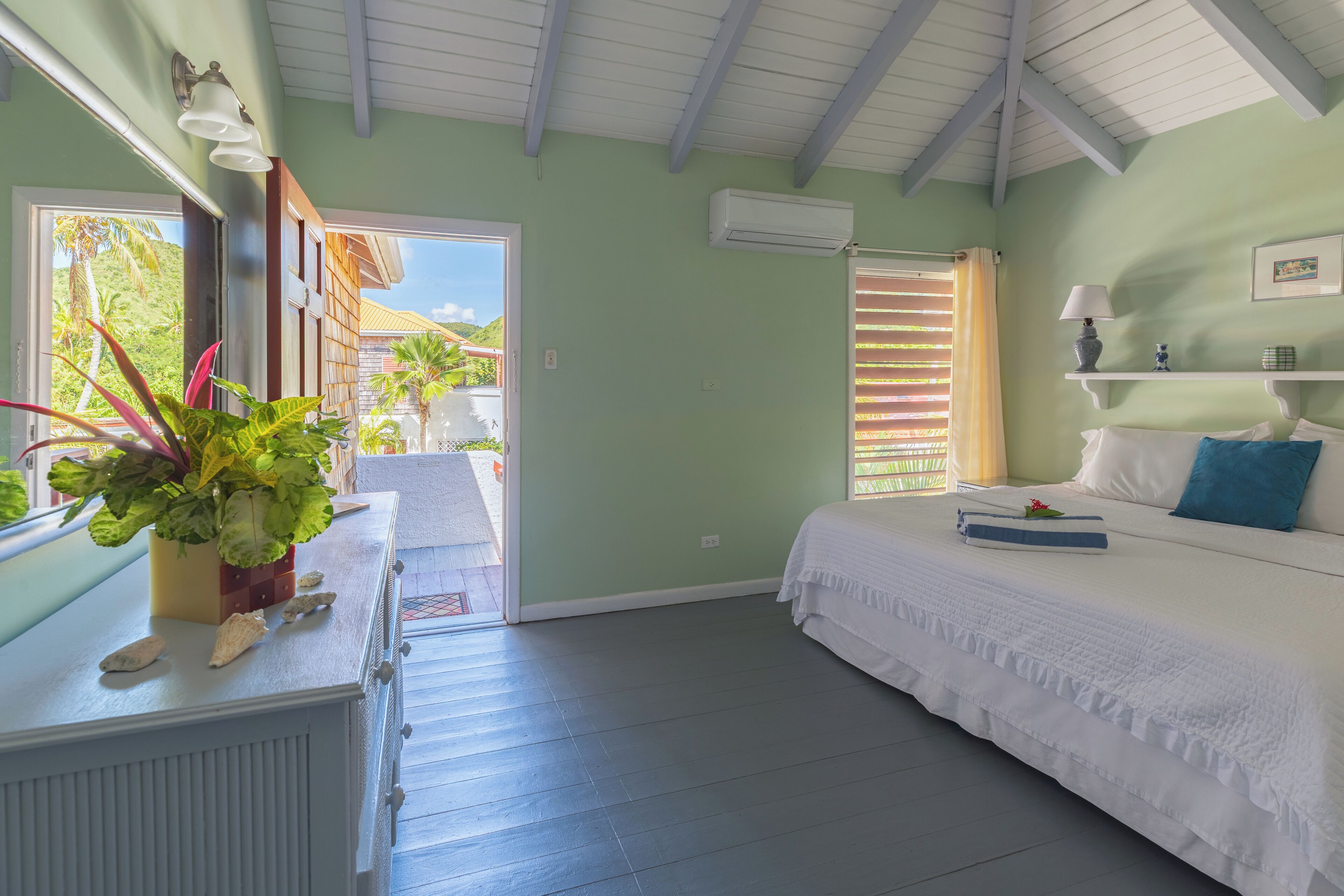 Una habitación con cama, cómoda, ventana con vista a vegetación y aire acondicionado.