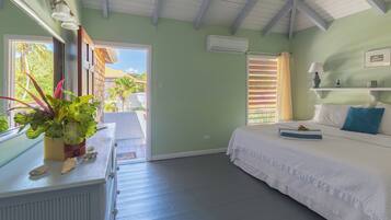 Una habitación con cama, cómoda, ventana con vista a vegetación y aire acondicionado.