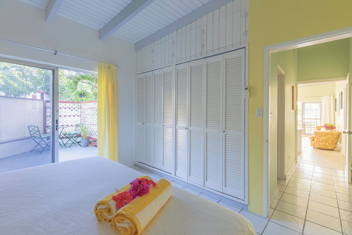 A hotel room with a bed, a balcony with a table and chairs, and a wardrobe.