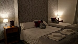 A hotel room with two beds, each with a lamp, a nightstand, and a mirror.