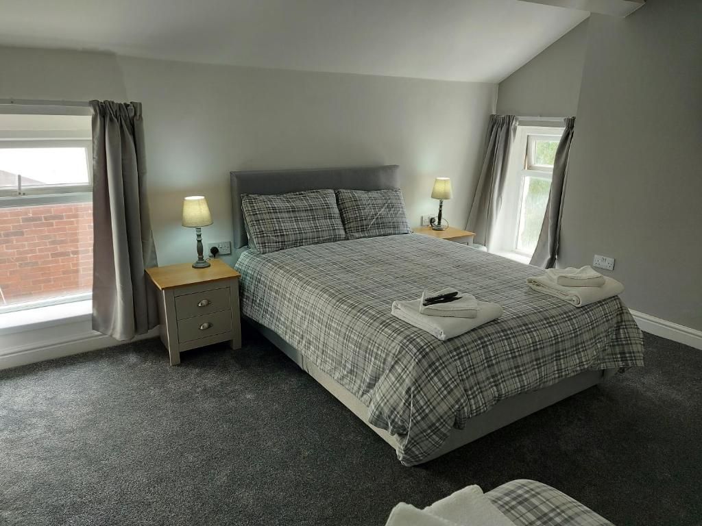 A bedroom with a bed, two bedside tables, a window, and curtains.