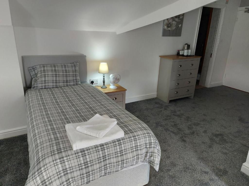 Ein Schlafzimmer mit Bett, Nachttisch, Lampe und Kommode.