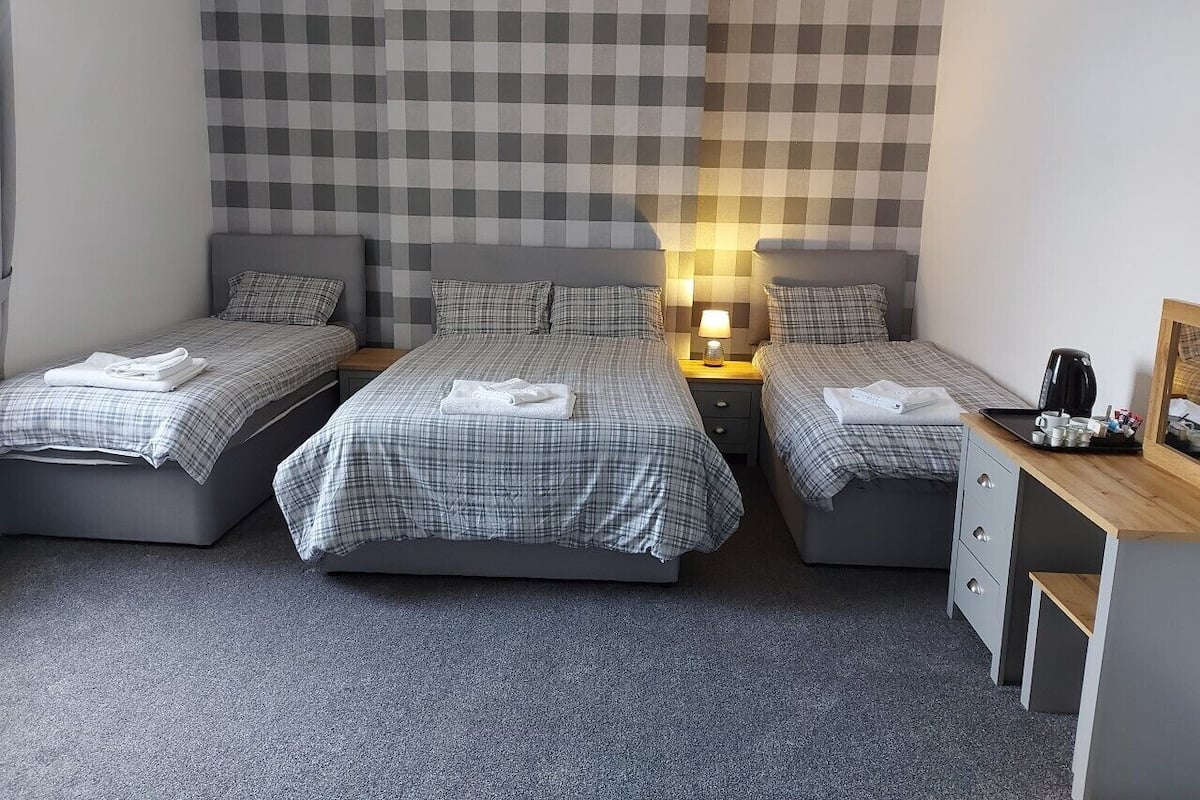 A hotel room with two single beds, a desk, and a nightstand with a lamp.