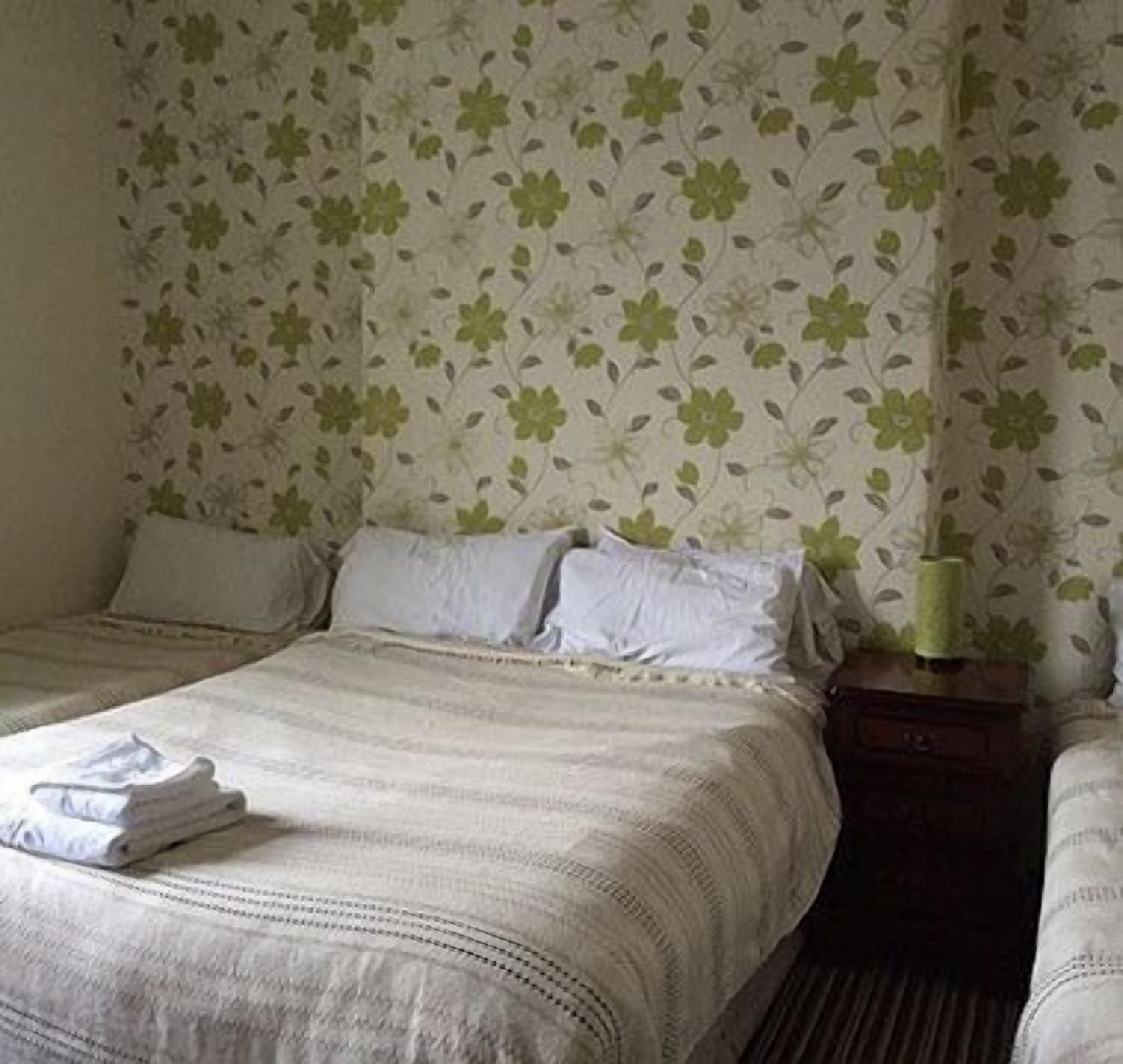 A hotel room with two beds, a nightstand, and a lamp.