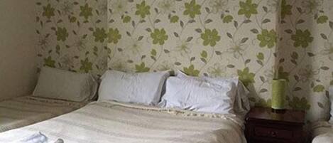 A hotel room with two beds, a nightstand, and a lamp.