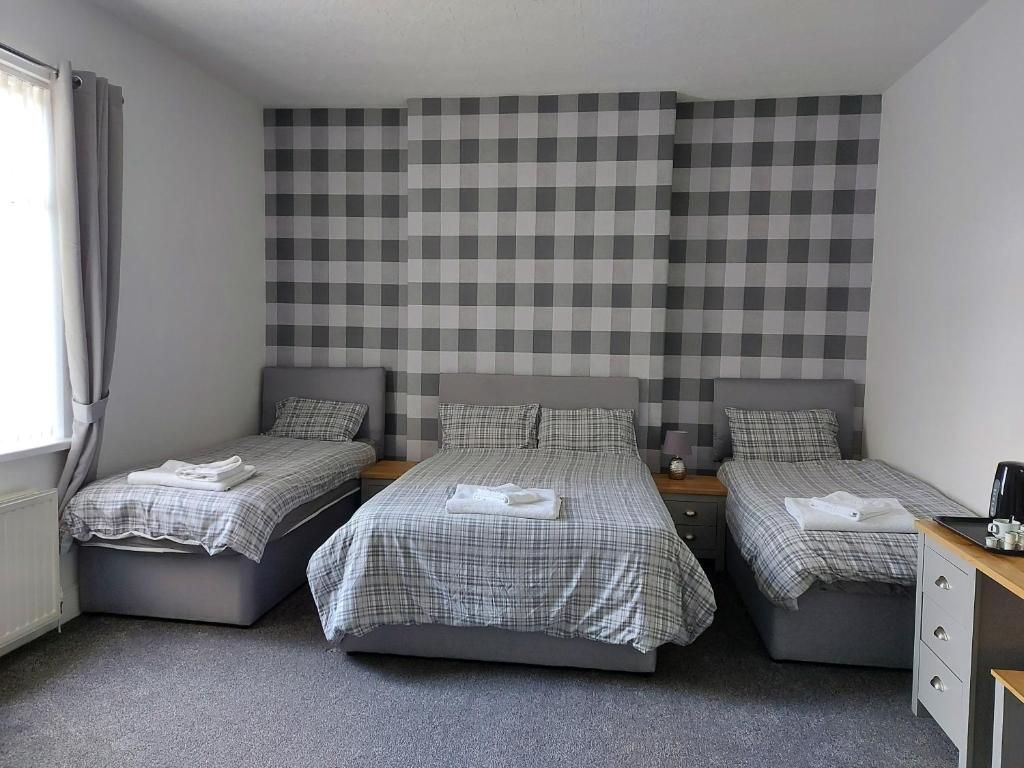 A room with three beds, a desk, and a radiator.