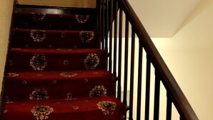 A staircase with a dark wooden handrail and red carpeted steps.