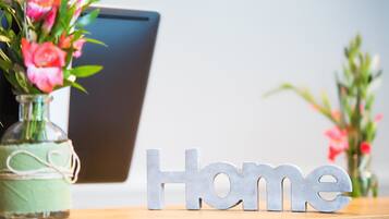 Un tavolo in legno con un vaso di fiori rosa e un cartello metallico con la scritta 'Home'.