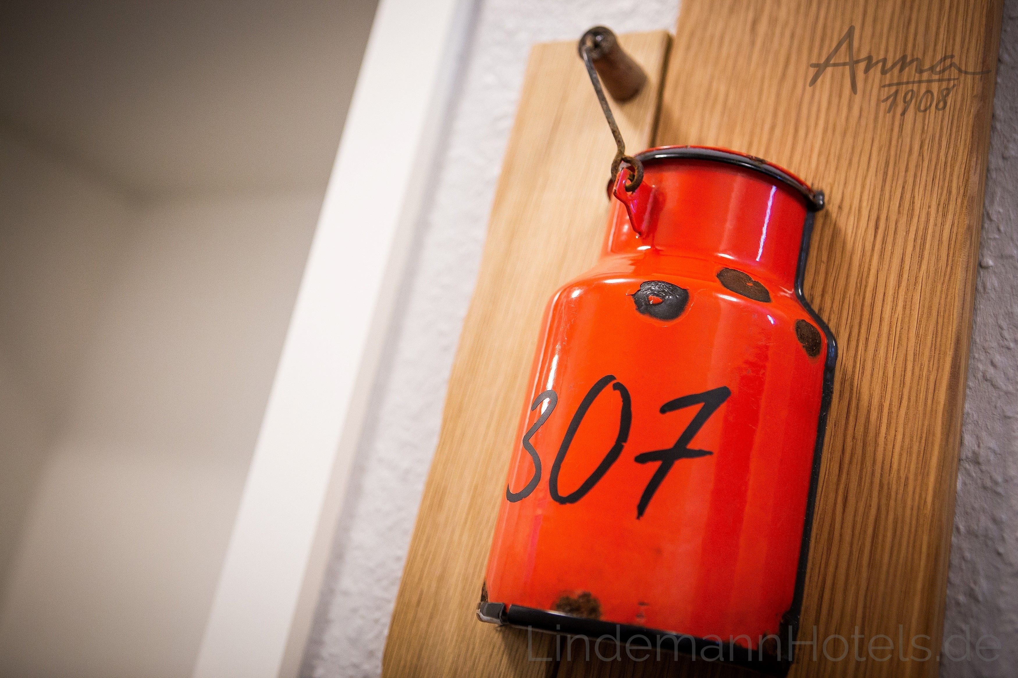 A red metal container with the number 307, mounted on a wooden board.