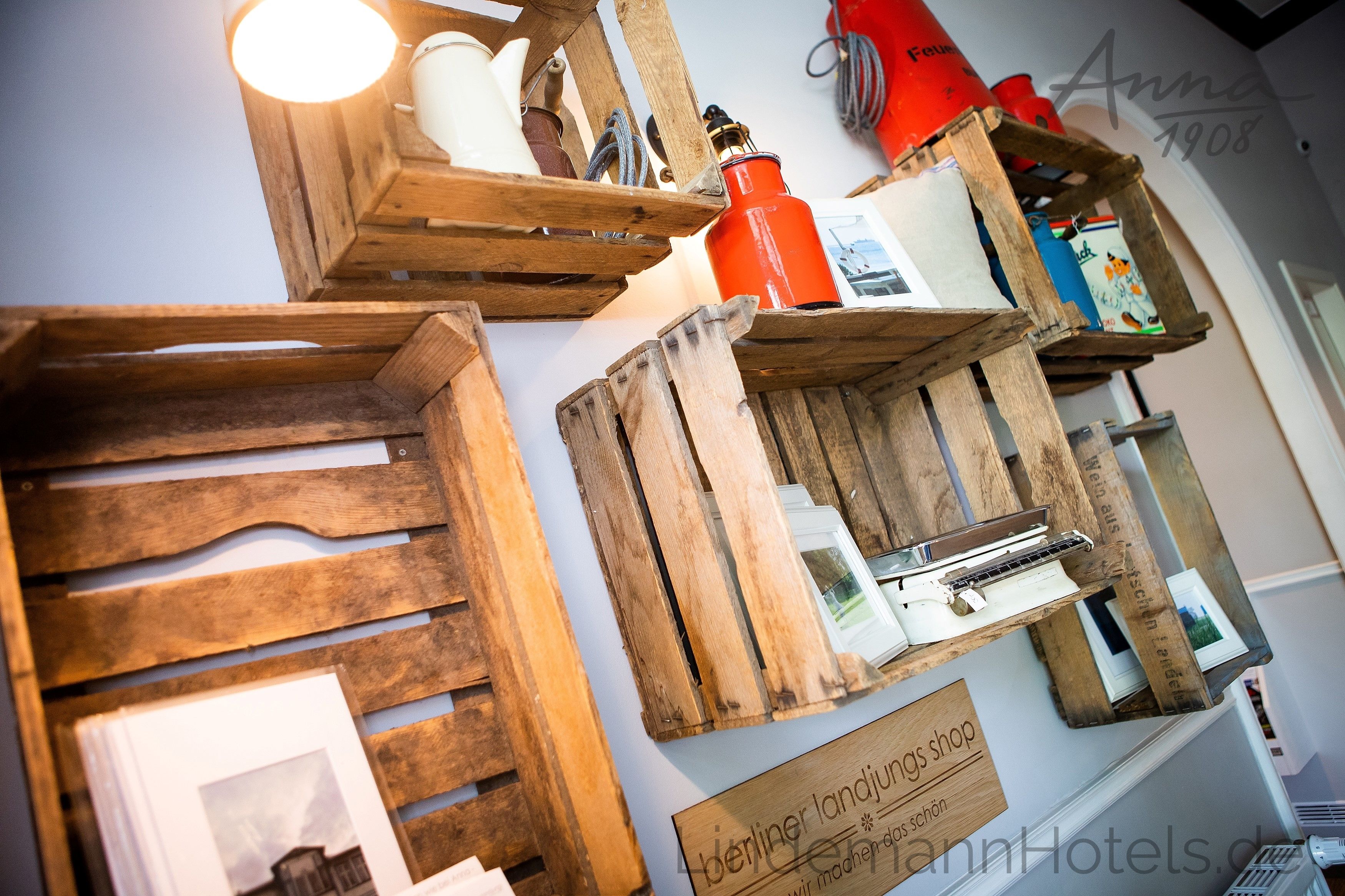 Des étagères en bois, sur lesquelles sont disposés divers objets, notamment une bouteille rouge et une enseigne indiquant « Berliner Landjungs shop ».