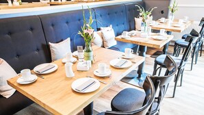 Un restaurante con mesas de madera, sillas negras y asientos acolchados azules.