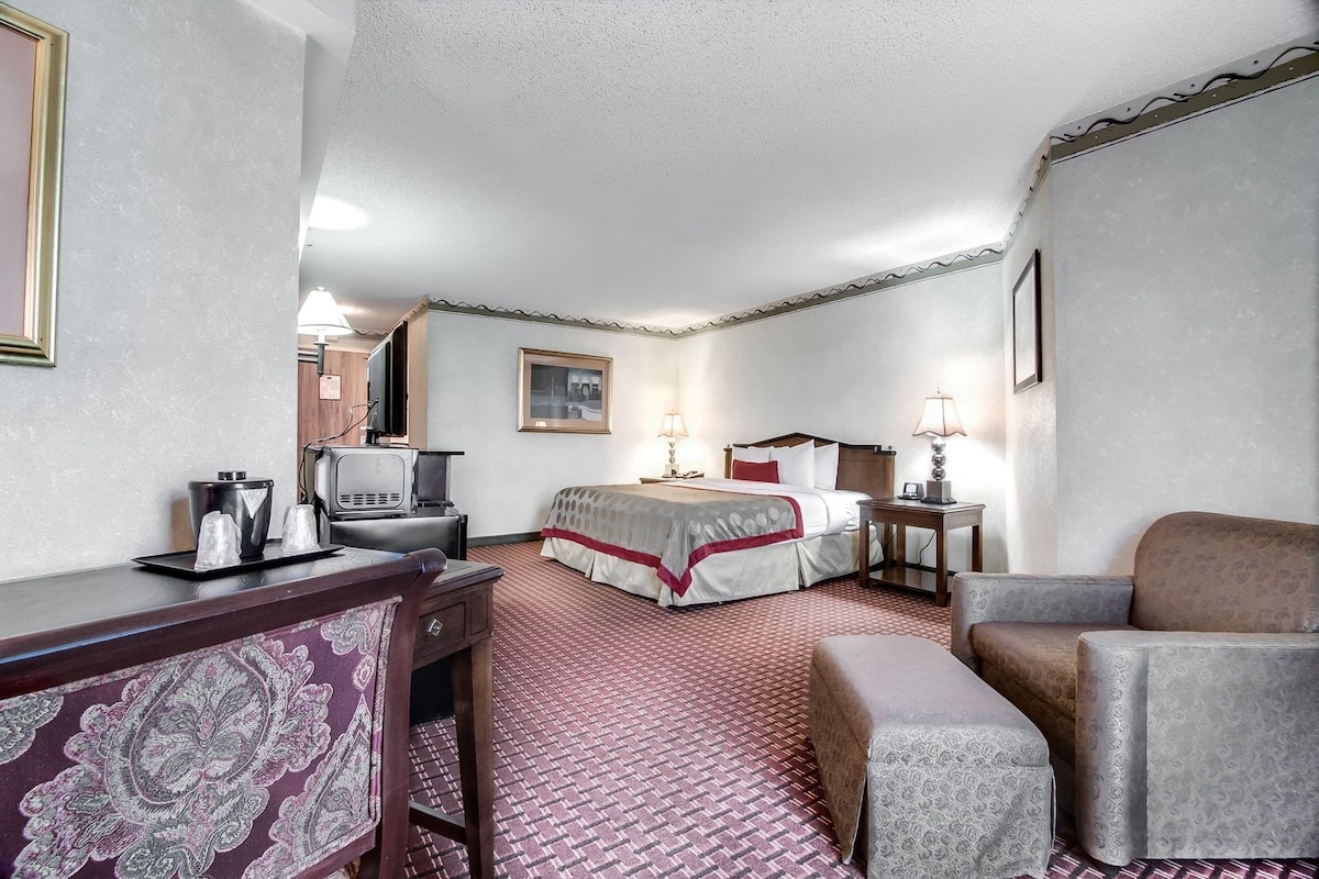 A hotel room with a bed, a desk with a telephone, a television, and a chair.