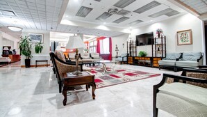 A spacious living room with a large sofa set, a coffee table, and a TV mounted on the wall.