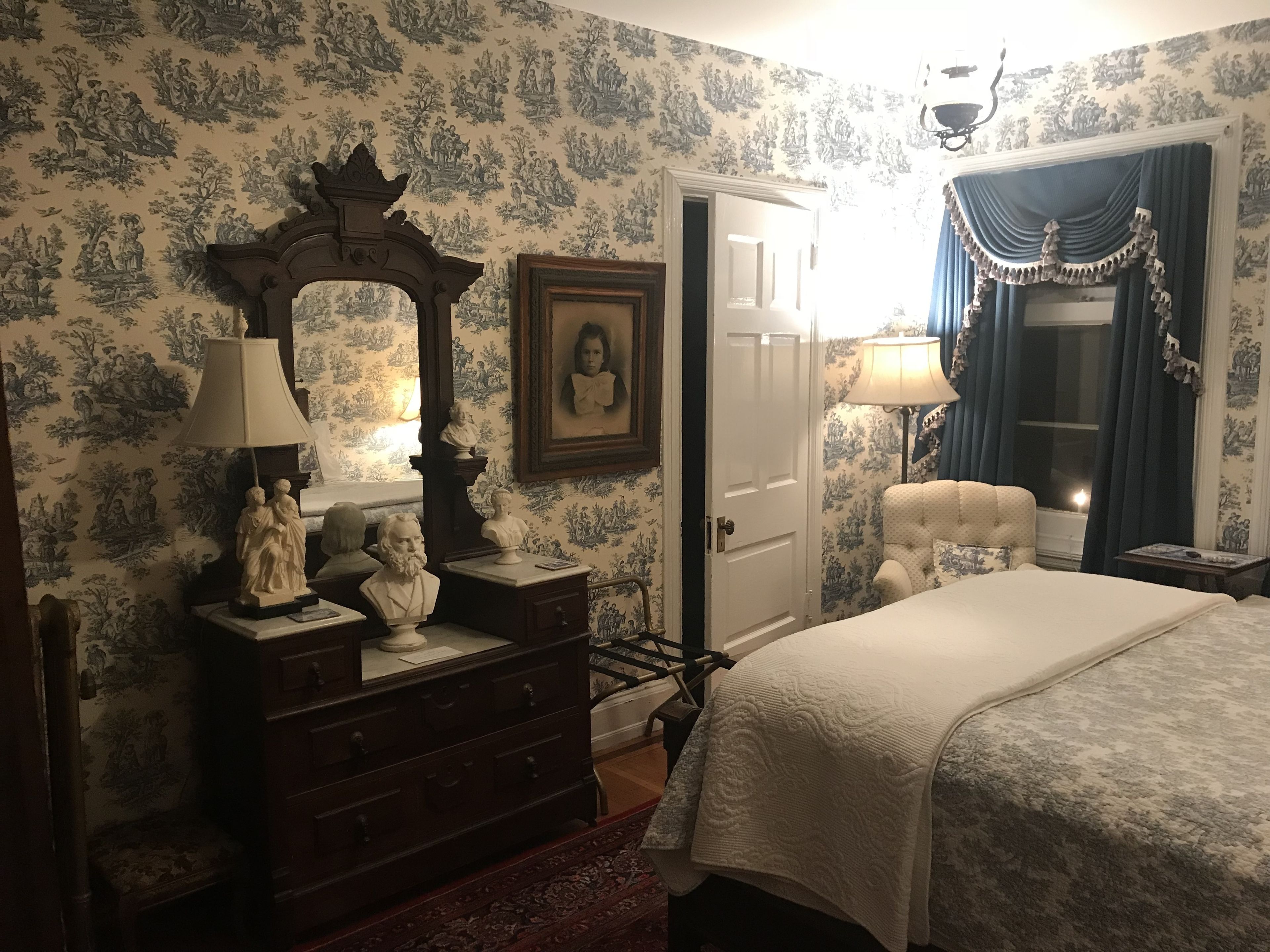 A bedroom with a bed, dresser, mirror, and two lamps.
