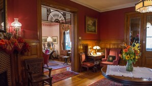 Une pièce à l’ambiance traditionnelle, avec des meubles en bois, une table à manger agrémentée d’un vase de fleurs et un tapis rouge.