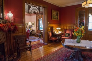 A traditional room with wooden furniture, a dining table with a vase of flowers, and a red carpet.