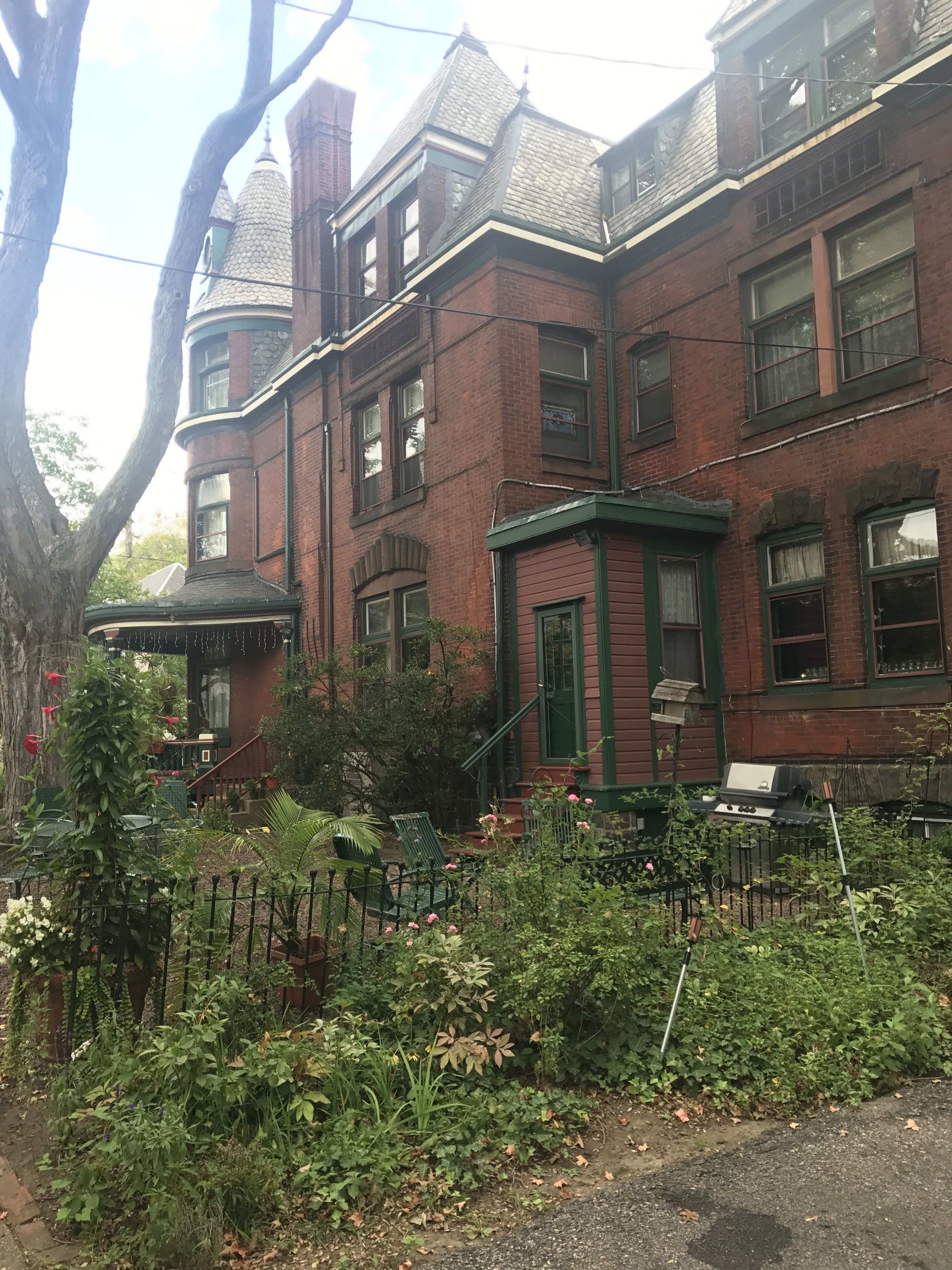 A Victorian-style brick house with a prominent turret and green trim.