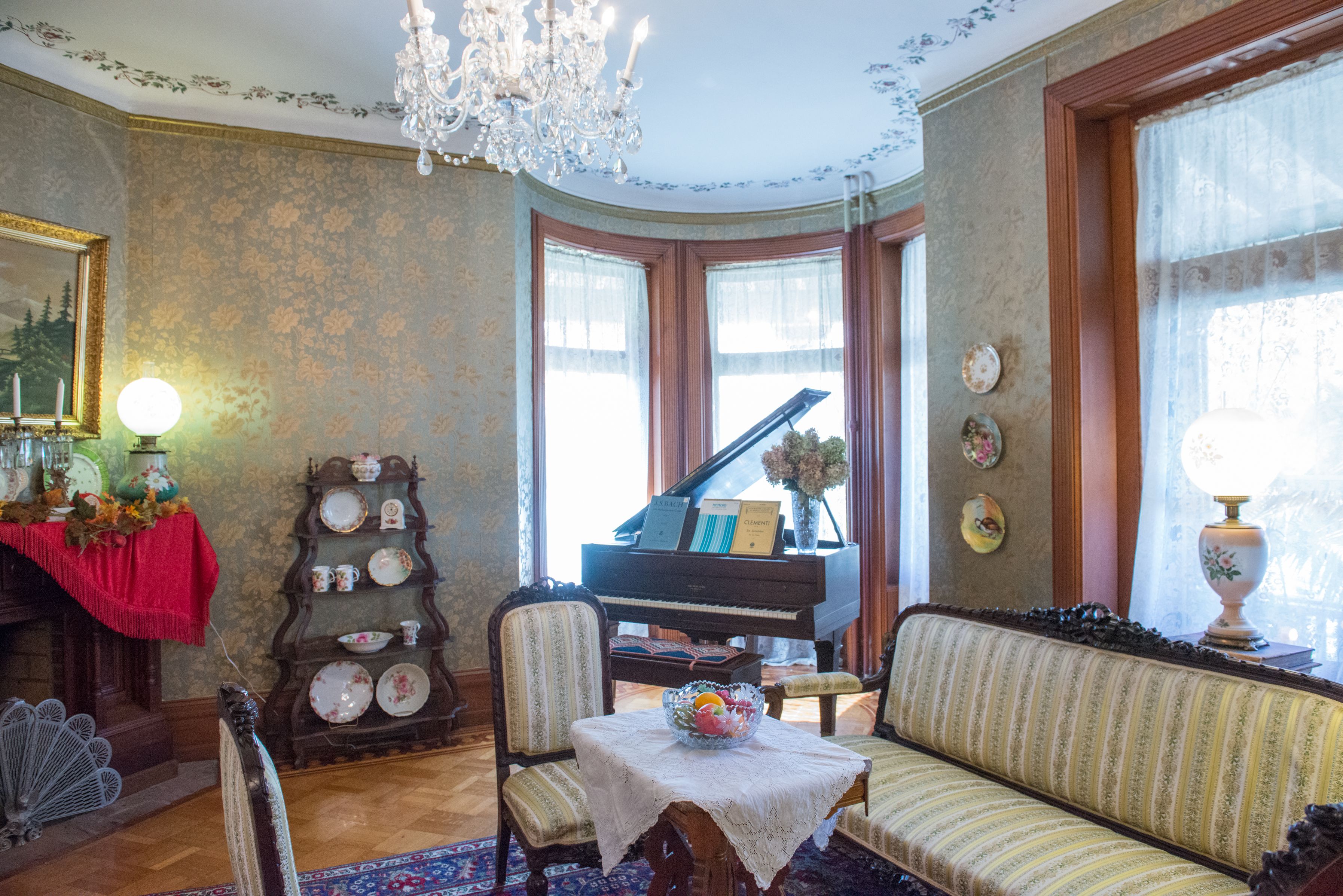Un salón elegante con un piano, una araña de cristal y un sofá.